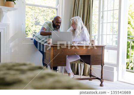 Couple planning wedding using laptop at home, discussing details and smiling Couple planning wedding using laptop at home, discussing details and smiling 135541669