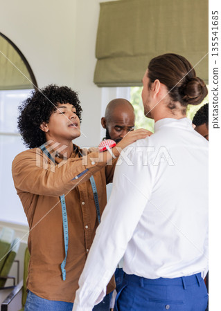 Tailor adjusting groom's suit, preparing for wedding ceremony with focus and care 135541685