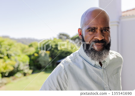 African American man standing outdoors, looking thoughtful in sunny garden setting African American man standing outdoors, looking thoughtful in sunny garden setting 135541690
