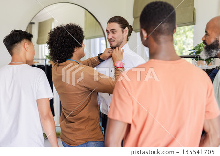 Groom getting ready with friends adjusting his tie, sharing joyful moments together 135541705