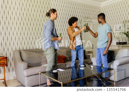 Friends celebrating with drinks in living room, enjoying joyful moment together 135541706