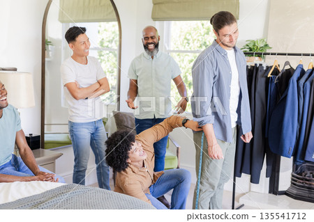 Groom getting ready with friends, laughing and adjusting sleeves in bedroom 135541712
