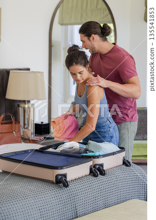 Couple packing suitcase on bed, preparing for wedding day celebration together 135541853