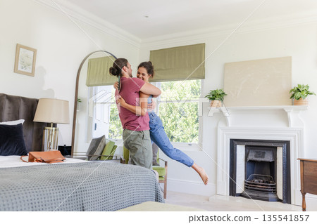 Couple embracing joyfully in cozy bedroom, celebrating special moment together Couple embracing joyfully in cozy bedroom, celebrating special moment together 135541857