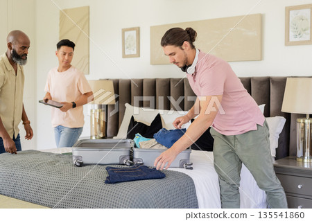 Friends packing suitcase in hotel room, preparing for wedding celebration together 135541860
