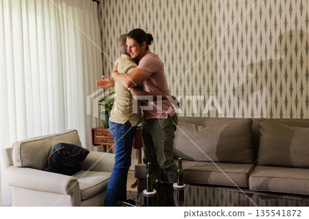 Friends embracing warmly in living room, celebrating special occasion together 135541872