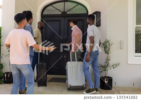 Friends arriving at house with luggage, excitedly entering for wedding celebration Friends arriving at house with luggage, excitedly entering for wedding celebration 135541882
