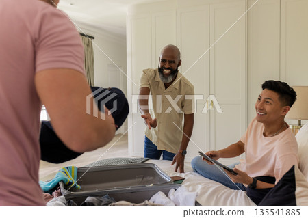 Friends packing suitcase together, smiling and enjoying time at home Friends packing suitcase together, smiling and enjoying time at home 135541885