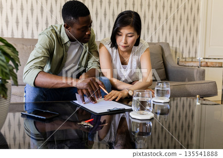Couple planning wedding details together at home, focused on notes and ideas 135541888
