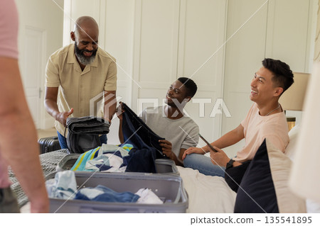 Packing clothes, diverse group of friends smiling and preparing for wedding trip Packing clothes, diverse group of friends smiling and preparing for wedding trip 135541895