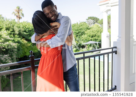 Couple embracing on balcony, enjoying sunny day at outdoor wedding venue 135541928