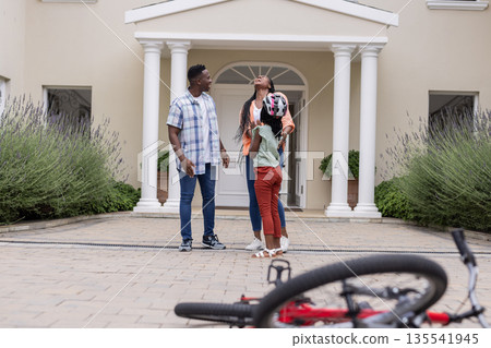 Outside home, African American family spending time together with bicycle in foreground 135541945