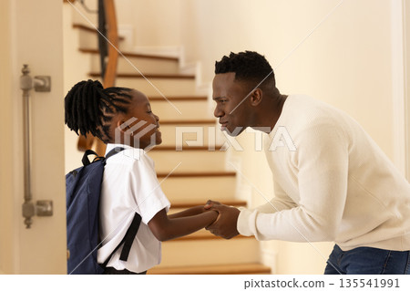 Father encouraging daughter with backpack before school on staircase at home Father encouraging daughter with backpack before school on staircase at home 135541991