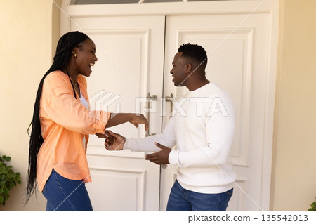 African American couple laughing and talking happily outside white double doors African American couple laughing and talking happily outside white double doors 135542013