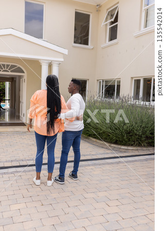 African American couple standing outside house, embracing and enjoying view 135542014