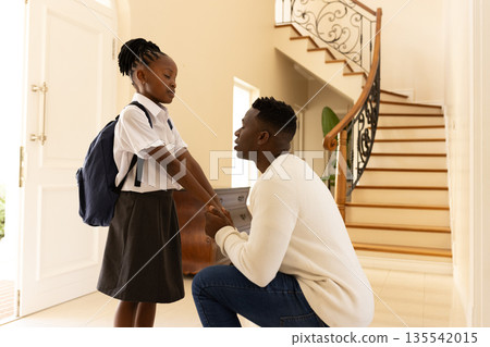 African American father kneeling, encouraging daughter with backpack before school African American father kneeling, encouraging daughter with backpack before school 135542015