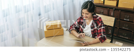 Banner Online seller Close up hands Young asian woman typing laptop keyboard checking online order on stock delivery package. Asian woman startup small business at home office with copy space Banner Online seller Close up hands Young asian woman typing laptop keyboard checking online order on stock delivery package. Asian woman startup small business at home office with copy space 135542275