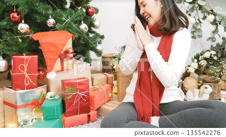 Close up woman hands wrap present gift in cozy living room. Woman wrapping christmas gift box under xmas tree. Asian woman decor bauble ball christmas tree in xmas holiday winter seasonal celebration Close up woman hands wrap present gift in cozy living room. Woman wrapping christmas gift box under xmas tree. Asian woman decor bauble ball christmas tree in xmas holiday winter seasonal celebration 135542276