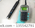 Probe status og pH meter or conductometer in woman hand in gloves. 135542791