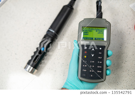 Probe status og pH meter or conductometer in woman hand in gloves. Probe status og pH meter or conductometer in woman hand in gloves. 135542791