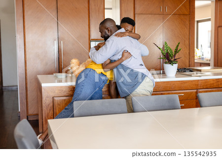 Family embracing warmly in modern kitchen, sharing joyful moment together 135542935