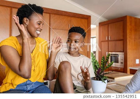 Mother and son enjoying playful moment together in modern kitchen at home Mother and son enjoying playful moment together in modern kitchen at home 135542951
