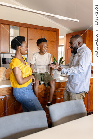 Happy family enjoying conversation in modern kitchen, bonding and smiling together Happy family enjoying conversation in modern kitchen, bonding and smiling together 135542952