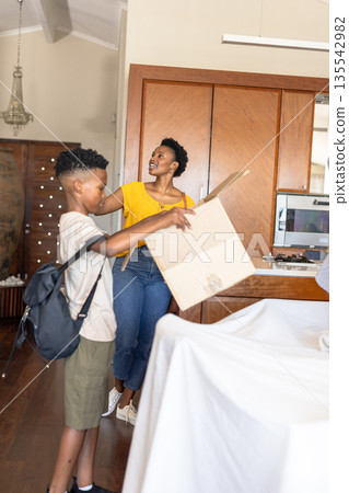 Mother and son unpacking cardboard box at home, smiling and enjoying time together Mother and son unpacking cardboard box at home, smiling and enjoying time together 135542982