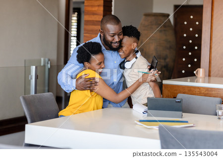 Family bonding at home, parents hugging son with headphones, smiling warmly 135543004