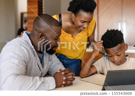 Parents helping son with homework using tablet at home, focusing on learning Parents helping son with homework using tablet at home, focusing on learning 135543009