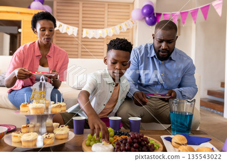 Family enjoying birthday party with cupcakes and fruit, celebrating together at home 135543022