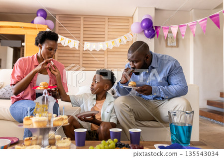 Family celebrating at home with cupcakes and festive decorations around them 135543034