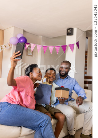 Family celebrating at home, taking selfie with gifts and festive decorations Family celebrating at home, taking selfie with gifts and festive decorations 135543043