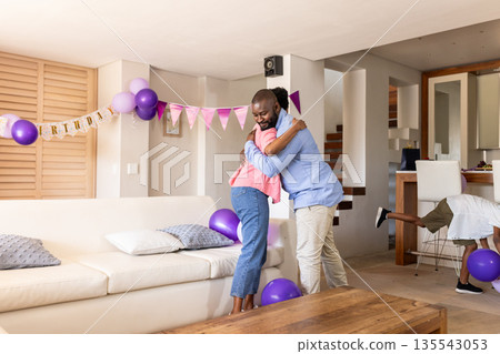 Family celebrating birthday at home, hugging with joy and festive decorations Family celebrating birthday at home, hugging with joy and festive decorations 135543053