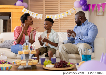 Celebrating birthday, happy family clapping and smiling with cake and decorations Celebrating birthday, happy family clapping and smiling with cake and decorations 135543066
