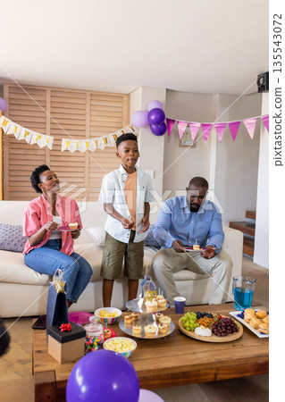 Family celebrating birthday at home with cupcakes and colorful decorations Family celebrating birthday at home with cupcakes and colorful decorations 135543072