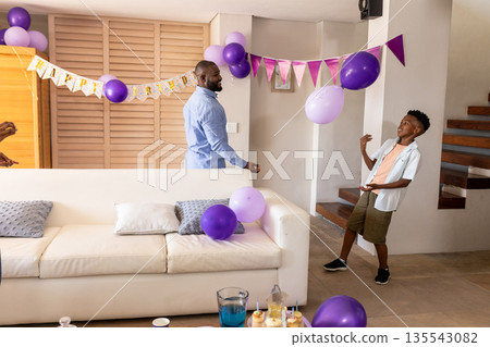 Celebrating birthday at home, African American father and son with balloons Celebrating birthday at home, African American father and son with balloons 135543082
