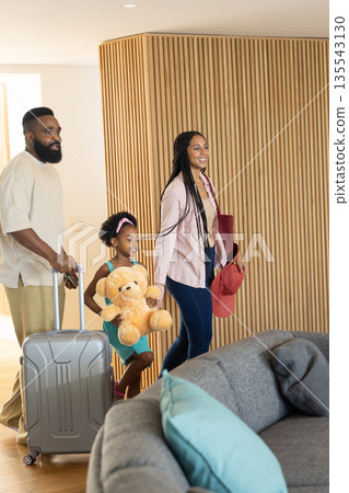 Family arriving at hotel, carrying luggage and smiling with excitement 135543130