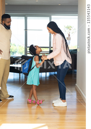 Mother and daughter sharing joyful moment at home with father watching 135543143