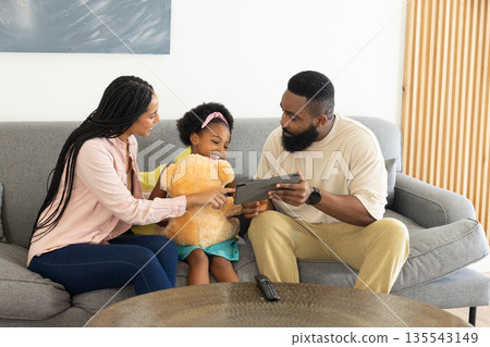 Family enjoying quality time on couch, using tablet and laughing together Family enjoying quality time on couch, using tablet and laughing together 135543149