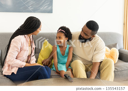 Happy family sitting on sofa at home, enjoying quality time together 135543157
