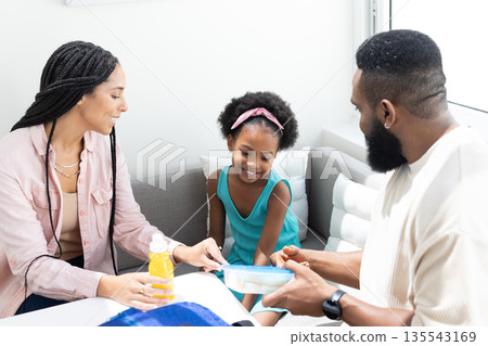 Family enjoying quality time together at home, sharing snacks and smiles Family enjoying quality time together at home, sharing snacks and smiles 135543169