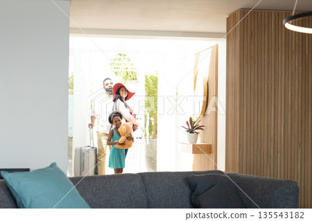 Family arriving home with suitcase and teddy bear, smiling and joyful Family arriving home with suitcase and teddy bear, smiling and joyful 135543182