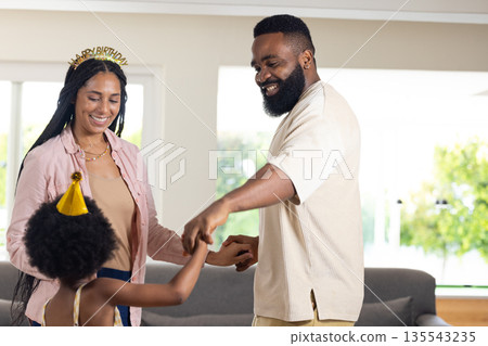 Family celebrating birthday at home, smiling and dancing together in living room 135543235