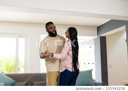 African American couple dancing happily at home, enjoying quality time together African American couple dancing happily at home, enjoying quality time together 135543258