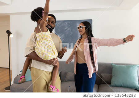 In living room, African American family dancing together, smiling and having fun 135543288