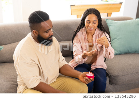 Receiving engagement ring, African American couple sitting on sofa, woman smiling Receiving engagement ring, African American couple sitting on sofa, woman smiling 135543290