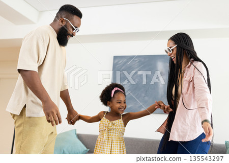 Family enjoying playful dance together at home, smiling and holding hands 135543297