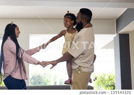 At home, African American parents playing with child, all smiling together 135543320