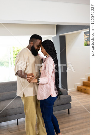 Couple dancing together at home, enjoying tender moment in living room 135543327